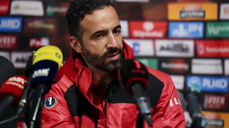 Rúben Amorim souriant lors de sa présentation officielle à l'AC Milan, portant un costume et une écharpe du club, devant un micro et le logo du club.