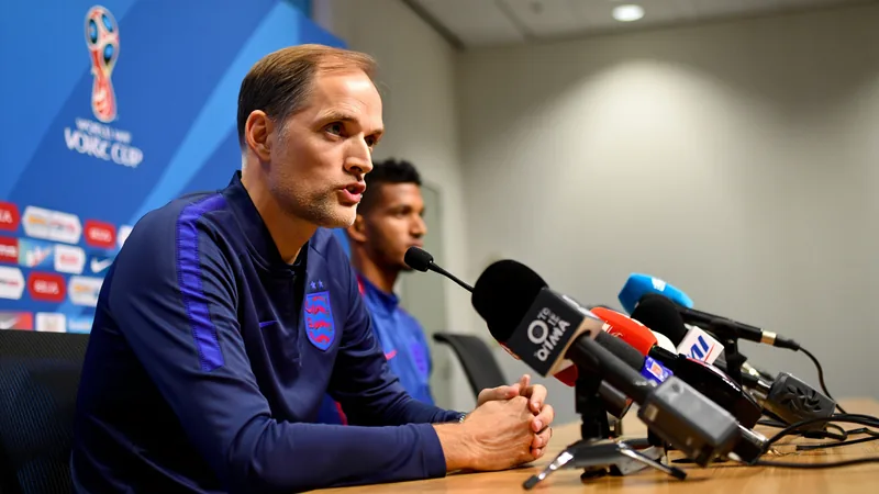 Thomas Tuchel, sélectionneur de l'Angleterre, souriant lors d'une conférence de presse à Mexico, avec un micro devant lui et un drapeau anglais en