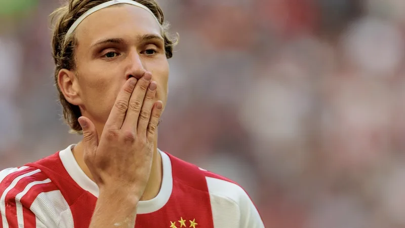 Ajax : Godts ménagé, le PSG en embuscade — Football World Cup News Mika Godts, ailier belge de l'Ajax, en action avec le ballon lors d'un match, portant le maillot rouge et blanc de l'Ajax.