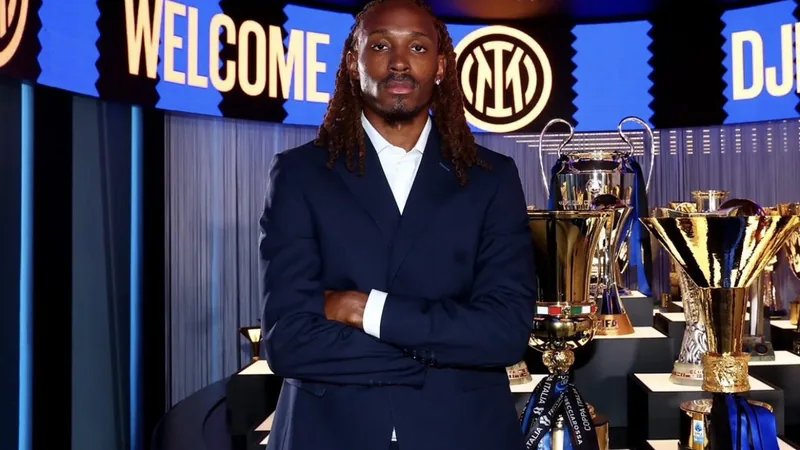 Djed Spence en tenue de l'Inter Milan, souriant, avec le logo du club en arrière-plan et le stade San Siro visible. — latest news and analysis.