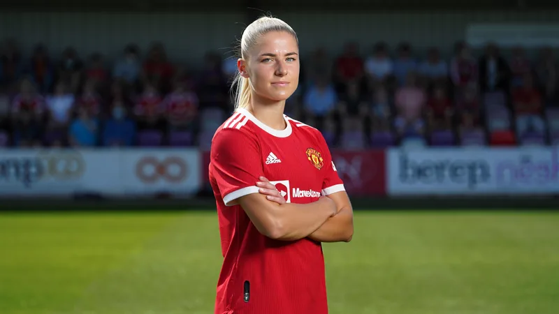 Gabby George proche de Brighton — Football World Cup News Gabby George en tenue de Manchester United, sur le terrain, avec le maillot rouge, prête à défendre, un ballon à ses pieds.