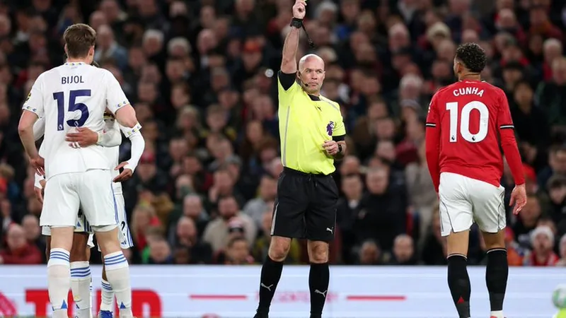 Polémique Balogun : Webb inquiet pour les arbitres — Football World Howard Webb, directeur de l'arbitrage, s'exprimant lors d'une conférence de presse sur la polémique Balogun, avec un micro devant lui.