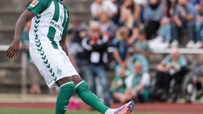 Karim Coulibaly, jeune défenseur du Werder Brême, en action lors d'un match de Bundesliga, portant le maillot vert et blanc.
