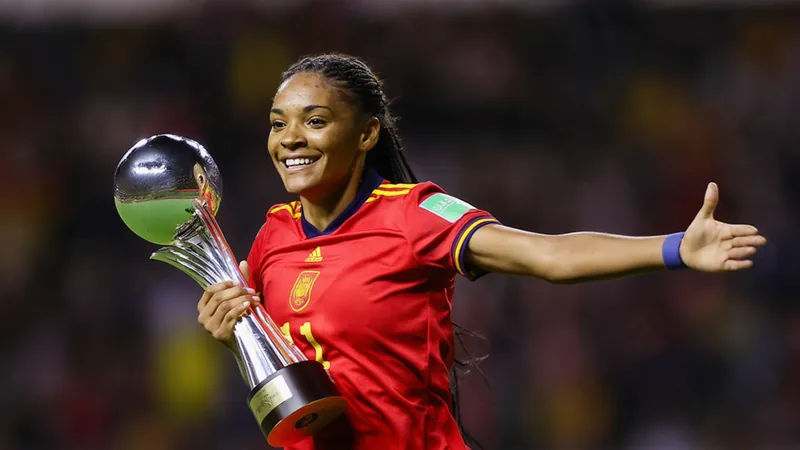 Joueuses de football célébrant une victoire sur le terrain, avec des confettis tombant et un trophée doré au premier plan.