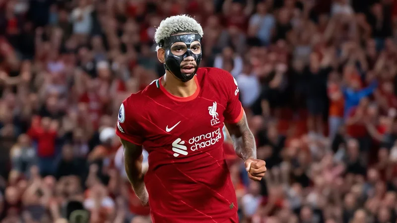 Araujo à Liverpool : accord finalisé — Football World Cup News Ronald Araujo en maillot du FC Barcelone, souriant, posant avec un maillot de Liverpool à Anfield, sous les projecteurs.