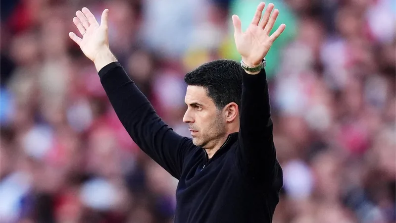 Mikel Arteta, entraîneur d'Arsenal, en costume sombre, regardant pensivement le terrain lors d'un match à l'Emirates Stadium.