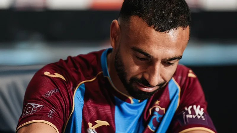Mo Salah signe à Trabzonspor : accord pour deux ans — Football World Mohamed Salah en tenue de Liverpool, souriant, tenant un maillot de Trabzonspor, avec le stade du club en arrière-plan. — latest news and analysis.