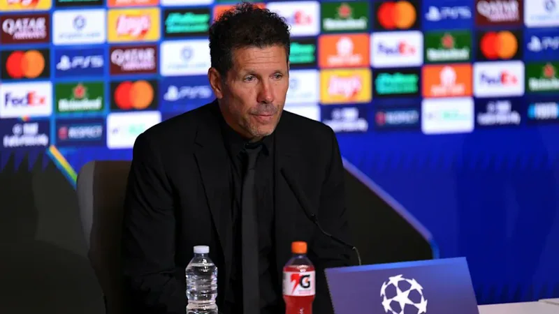 Simeone réagit aux chants insultants envers Julián Alvarez — Football Diego Simeone, entraîneur de l'Atlético Madrid, en costume sombre, regardant le terrain lors d'un match, avec des supporters en arrière-plan.