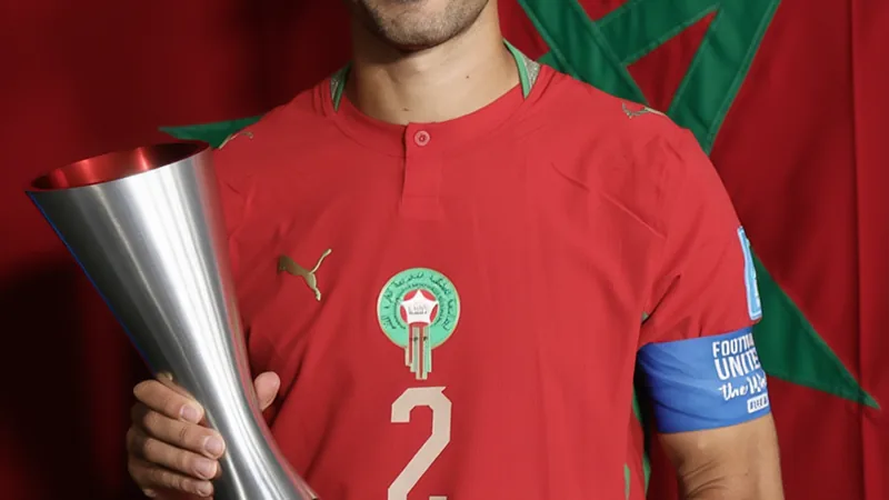 Achraf Hakimi, jogador de Marrocos, comemora após receber o prêmio de Melhor em Campo da FIFA, com a torcida ao fundo. — latest news and analysis.