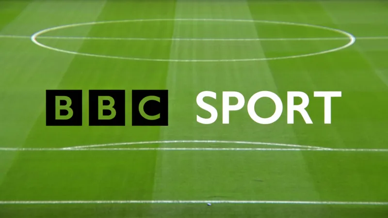 BBC renova acordo para jogos de Escócia, País de Gales e Irlanda do Estádio de futebol com bandeiras da Escócia, País de Gales e Irlanda do Norte hasteadas, torcedores vibrantes e o logotipo da BBC no placar