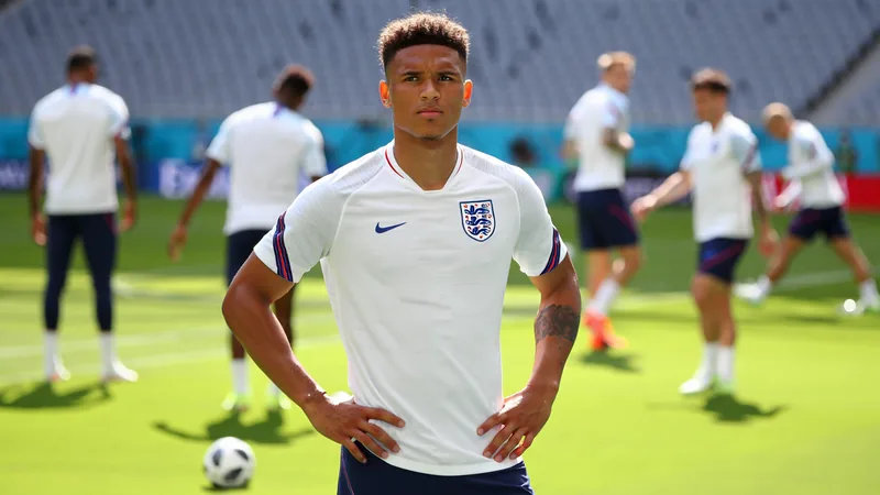 Bellingham titular, mas sem Guehi: o provável onze de Inglaterra Jude Bellingham com a camisola de Inglaterra durante um treino, com colegas ao fundo e bandeiras inglesas no estádio. — latest news and analysis.