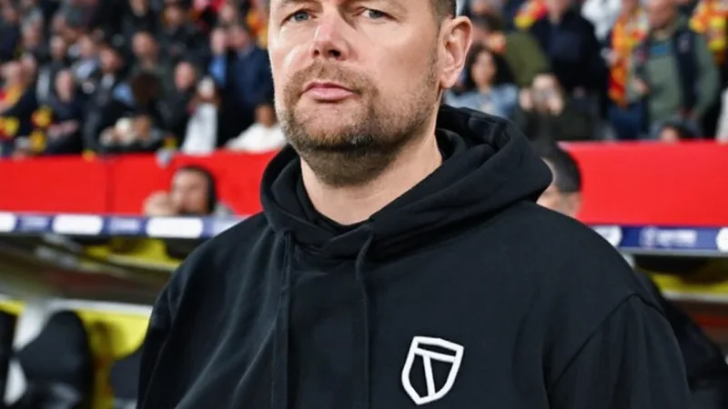 Crystal Palace e Lens negociam contratação de Pierre Sage como Pierre Sage, treinador de futebol francês de 45 anos, vestindo terno e gravata, sorrindo durante uma entrevista coletiva no estádio do RC Lens.
