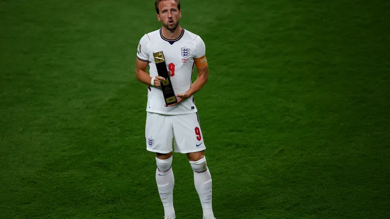 Harry Kane eleito Melhor em Campo pela FIFA — Football World Cup News Harry Kane comemora um gol pela Inglaterra no Estádio de Wembley, com a torcida ao fundo e a bandeira inglesa sendo agitada.