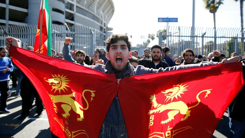 Torcedores iranianos agitam bandeiras do Leão e Sol e da República Islâmica em arquibancadas do Los Angeles Stadium durante partida da Copa do Mundo.