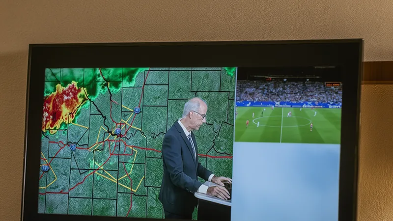Jogo da Escócia interrompido por tempestade severa em Kansas City Estádio em Kansas City com telão exibindo alerta de tempestade severa, torcedores deixando arquibancadas em direção a áreas cobertas, céu escuro e
