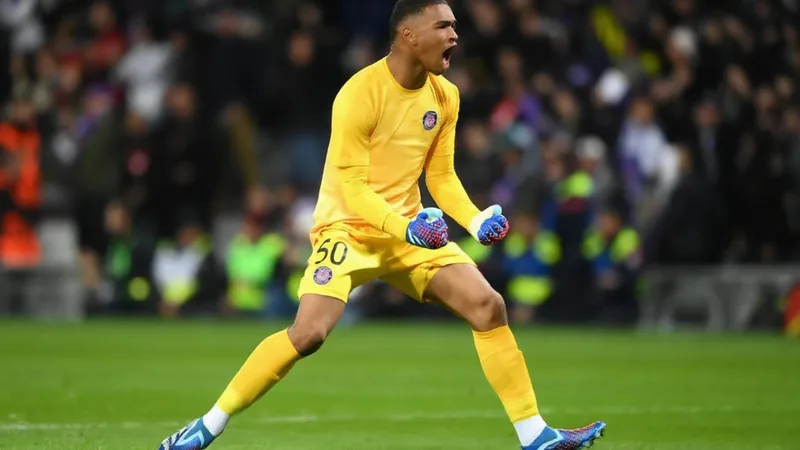 Jovem guarda-redes Guillaume Restes em ação pelo Toulouse, vestindo o equipamento vermelho e branco, num estádio lotado.