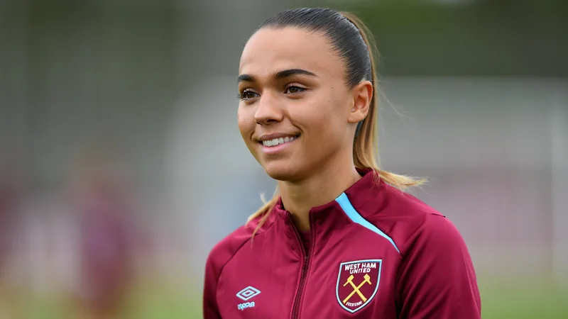 West Ham contrata defesa suíça Nadine Riesen por três temporadas Jogadora de futebol feminino com camisa do West Ham segurando a camisa do clube ao lado da treinadora Rita Guarino em sala de imprensa