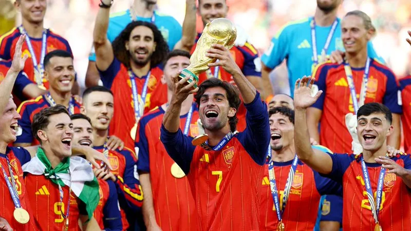 Espanha bicampeã mundial feminina: vitória sobre Argentina — Football Jogadoras espanholas comemorando o gol do título mundial no MetLife Stadium, com a bandeira da Espanha ao fundo e torcedores argentinos nas
