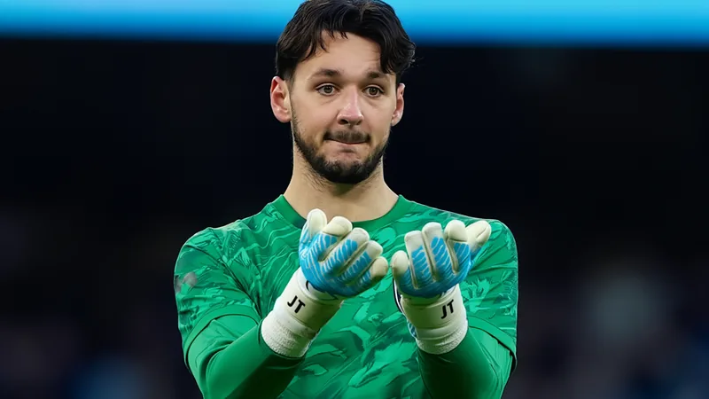 Leeds United negocia com Manchester City por James Trafford James Trafford, goleiro do Manchester City, em ação durante uma partida, vestindo o uniforme azul celeste, com o estádio ao fundo.