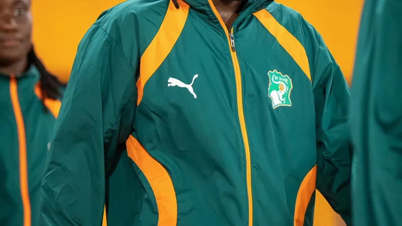 Rosemonde Kouassi lidera a Costa do Marfim rumo ao Brasil 2027 Rosemonde Kouassi, atacante da Costa do Marfim, comemora um gol vestindo a camisa laranja da seleção, em um estádio lotado de torcedores.