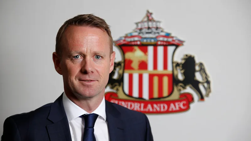 Sunderland feminino nomeia James Gray, ex-FA, como CEO — Football James Gray em traje formal, sorrindo, com o logotipo do Sunderland ao fundo em um escritório moderno. — latest news and analysis.
