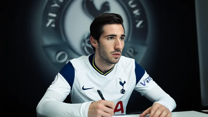 Sandro Tonali vestindo a camisa do Tottenham Hotspur em um estúdio de fotografia, sorrindo e segurando a camisa com o número 8