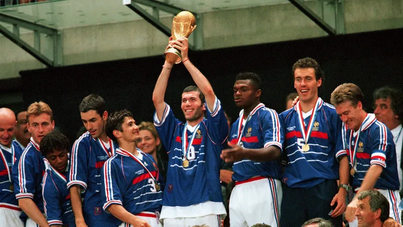 Zinedine Zidane em campo com a camisa da França, erguendo a taça da Copa do Mundo de 1998 no Stade de France, sob o céu noturno de Paris.