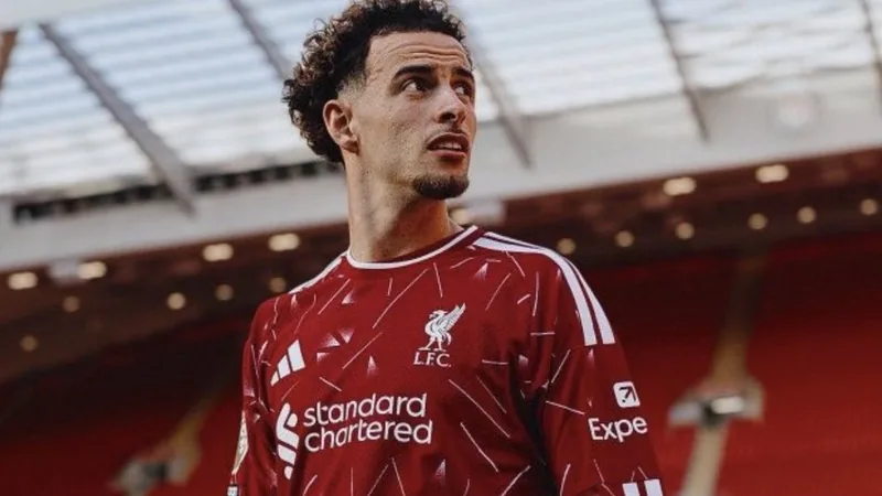Curtis Jones fora dos amistosos; Inter segue interessado — Football Curtis Jones, meio-campista do Liverpool, em campo com a camisa vermelha, durante uma partida, com o estádio Anfield ao fundo.