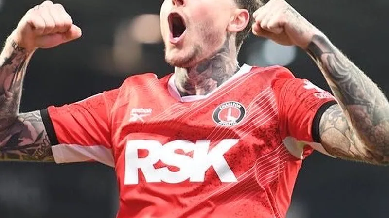 Dykes acerta com Millwall após várias propostas — Football World Cup Lyndon Dykes, atacante escocês, vestindo a camisa do Queens Park Rangers, comemora um gol em um estádio lotado, com torcedores ao fundo.