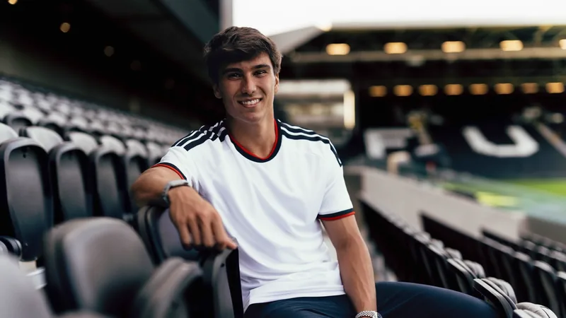 Gonzalo García, jovem avançado espanhol, vestindo a camisa do Fulham, sorrindo em frente ao estádio Craven Cottage em Londres.