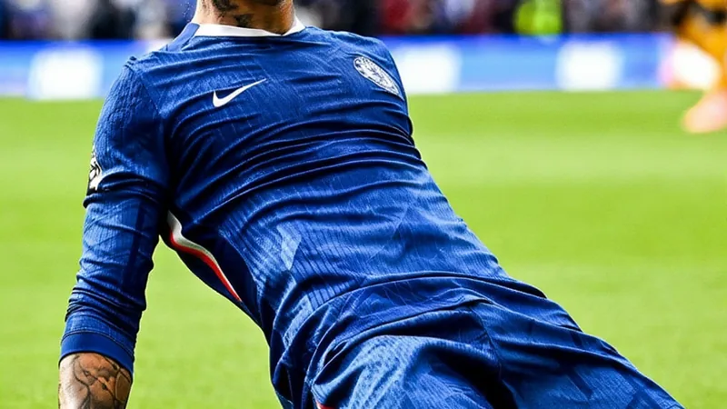 Enzo Fernández com a camisa do Chelsea durante uma partida, em um estádio lotado, com torcedores ao fundo e o gramado verde em destaque.