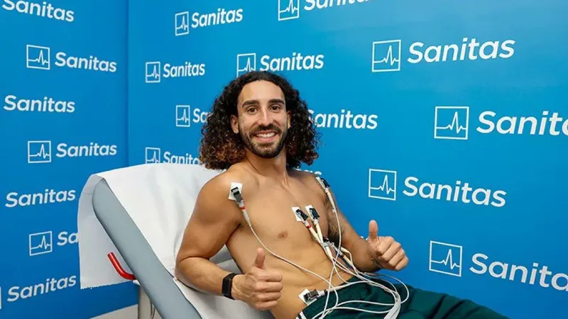 Marc Cucurella segurando a camisa do Real Madrid durante sua apresentação oficial no Santiago Bernabéu, com o gramado ao fundo.
