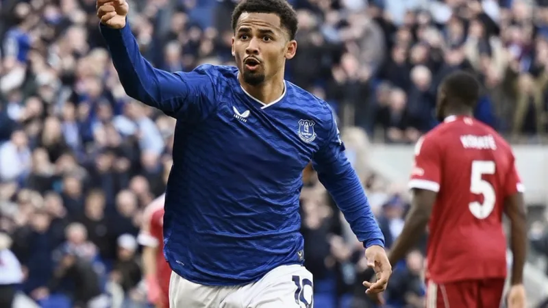 Iliman Ndiaye, extremo senegalês do Everton, com a camisola azul, a controlar a bola num relvado, com adeptos ao fundo. — latest news and analysis.
