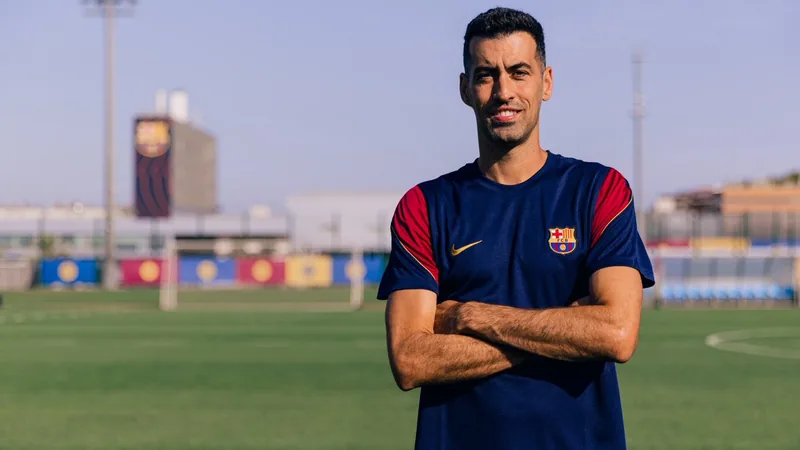 Sergio Busquets vestindo terno, ao lado de Juliano Belletti, no campo de treinamento do Barcelona B, com jovens jogadores ao fundo.